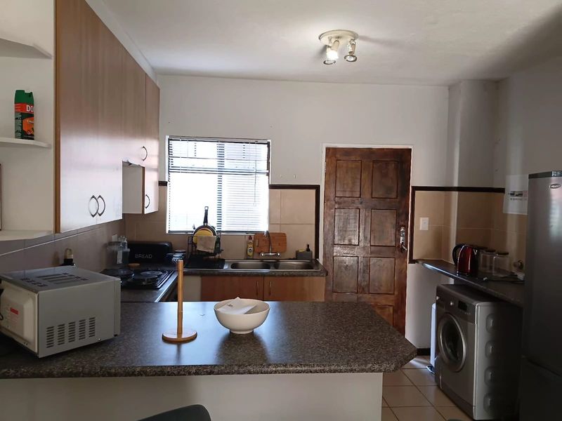 A functional kitchen featuring laminate cabinetry, laminate countertops, a double basin sink, and a built-in hob with tiled splashbacks.