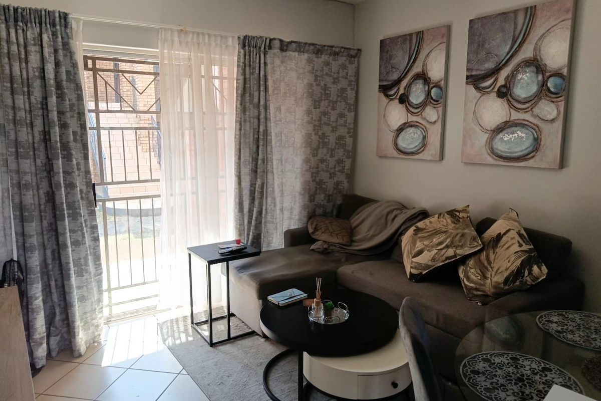 A living room area featuring tiled flooring and a sliding glass door with an integrated security gate providing access to the exterior.