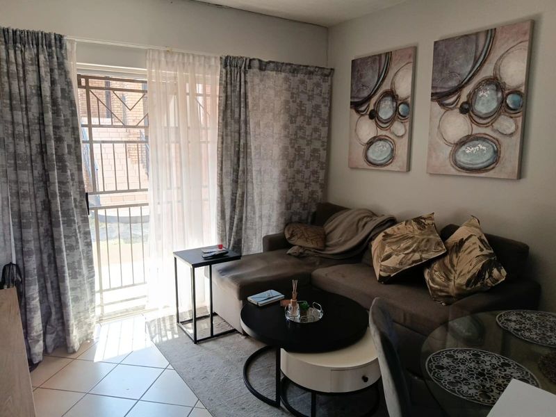 A living room area featuring tiled flooring and a sliding glass door with an integrated security gate providing access to the exterior.
