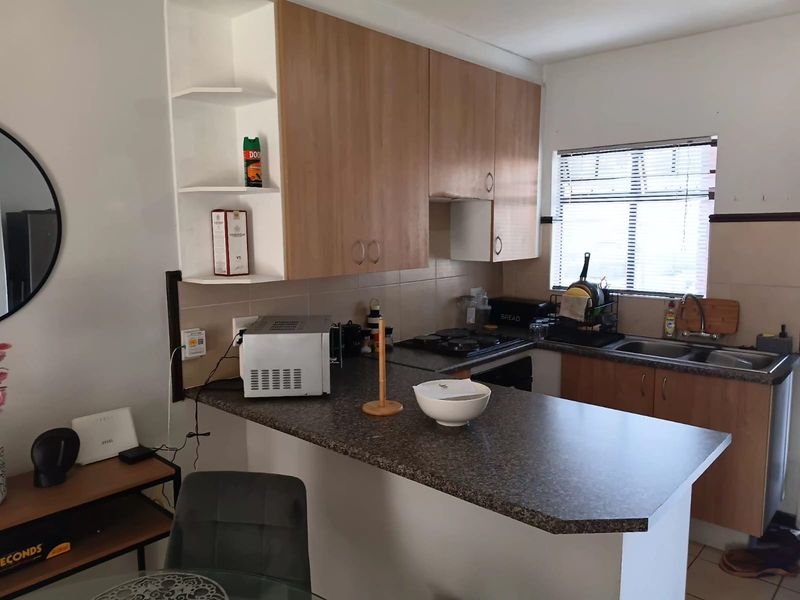 A functional kitchen featuring laminate cabinetry, dark countertops, a double bowl sink, and a built-in gas hob with oven.