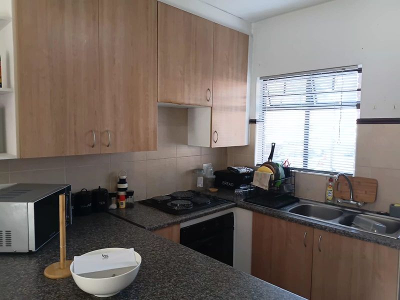 Functional kitchen featuring laminate cabinetry, granite countertops, built-in oven, gas hob, and a double bowl sink with a tiled backsplash.