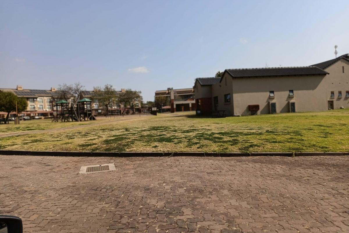 A view of the communal grounds within the apartment complex, featuring paved areas, landscaped lawns, and playground facilities.