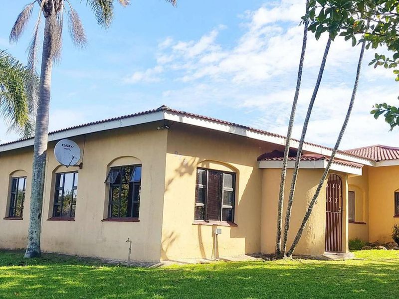 A view of the rear exterior of the house featuring a tiled roof, security gate, and established garden surroundings.