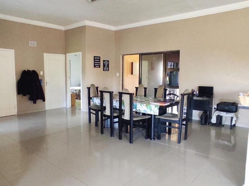 Spacious open-plan living and dining area featuring neutral wall tones, tiled flooring, and decorative ceiling cornicing.