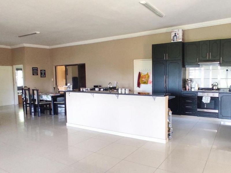 Spacious open-plan living area featuring a kitchen with dark cabinetry, a central island, and tiled flooring throughout.