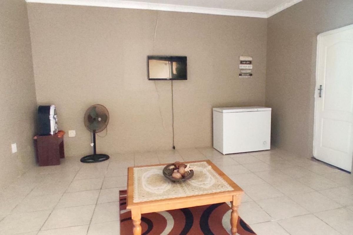 A living area featuring tiled flooring and a visible wall crack, offering a blank canvas for potential interior updates and renovation.
