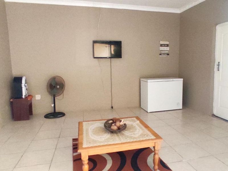 A living area featuring tiled flooring and a visible wall crack, offering a blank canvas for potential interior updates and renovation.