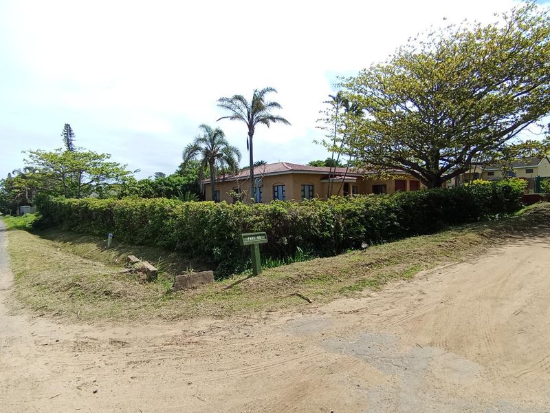 A street-level view of the property facade, featuring a tiled roof and established perimeter hedging, situated on a corner plot.