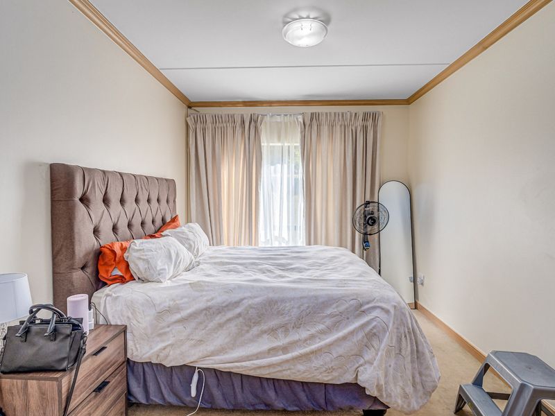 A functional bedroom featuring neutral wall tones, ceiling cornicing, and a central light fixture, providing a comfortable and well-lit sleeping space.