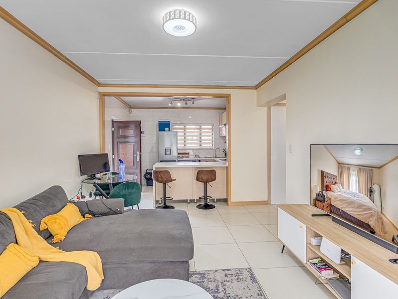 Open-plan living area featuring tiled floors and a functional kitchen with a breakfast island, creating a cohesive and practical living space.
