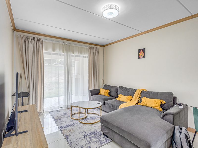 A bright living room featuring tiled flooring and a large sliding glass door that provides access to the outdoor area.