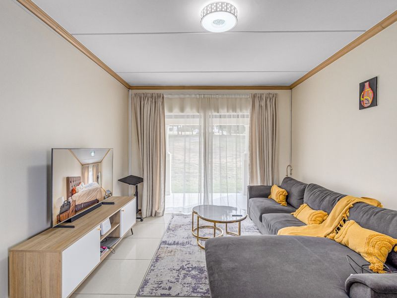 A bright living room featuring tiled flooring, crown molding, and a large sliding glass door providing access to the outdoor area.