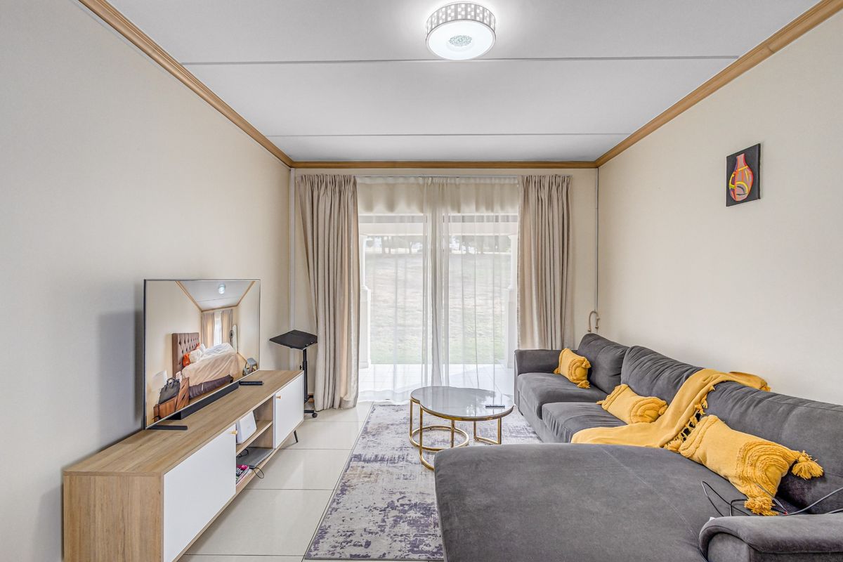 A bright living room featuring tiled flooring, crown molding, and a large sliding glass door providing access to the outdoor area.