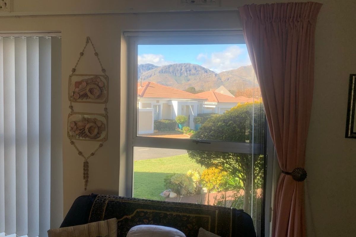 A view from a living room window looking out towards a residential street and mountain landscape.