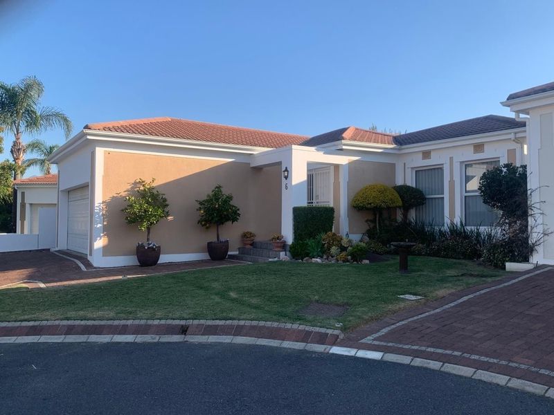 Front elevation of a well-maintained single-story house featuring a paved driveway, tiled roof, and landscaped garden area.