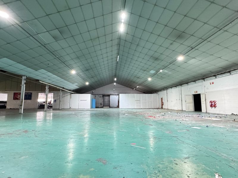 Large open-plan industrial warehouse space featuring high ceilings, painted concrete flooring, and steel structural columns, suitable for various commercial or storage applications.