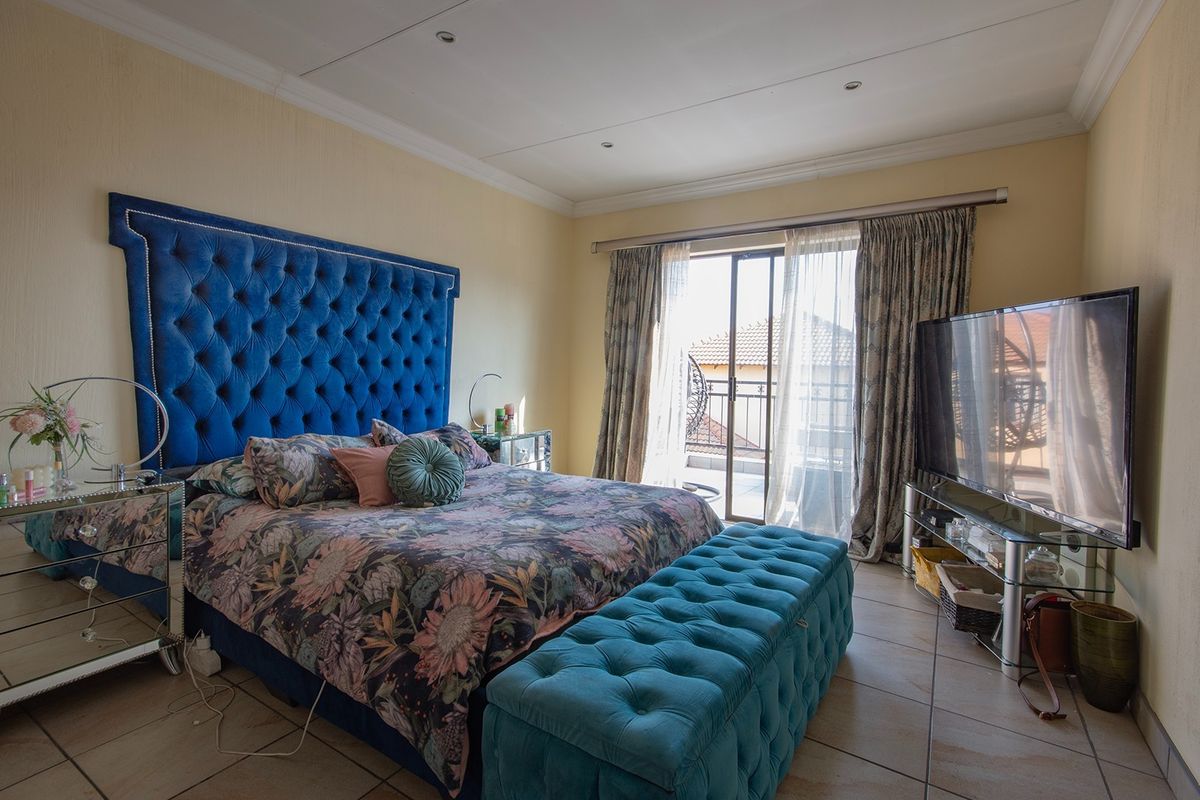 Spacious bedroom featuring tiled flooring, crown molding, and a sliding glass door providing access to a private balcony.
