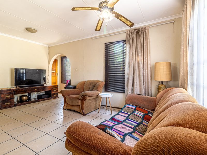 A living room featuring tiled flooring, a ceiling fan, and an arched doorway leading to an adjacent space.