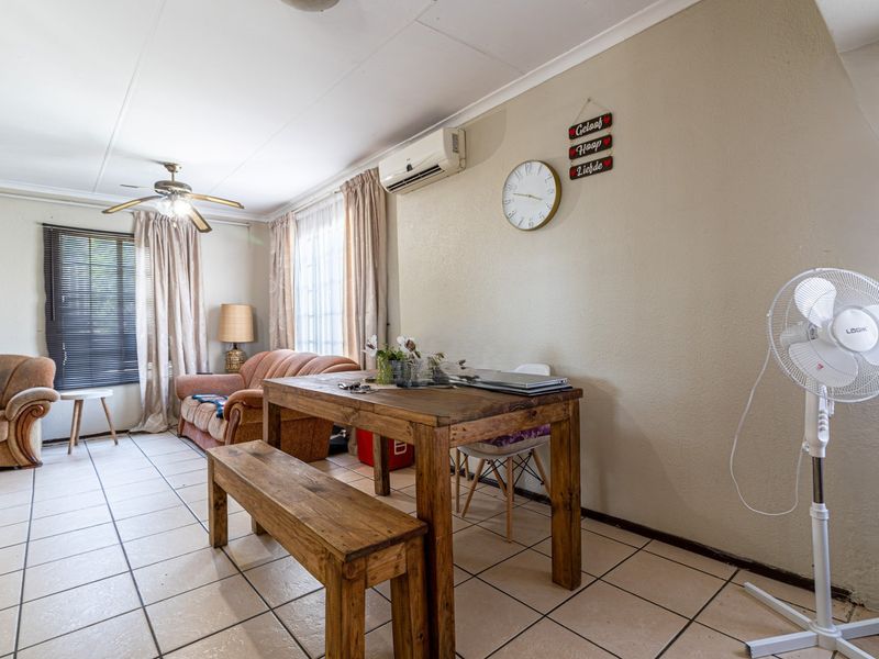 A living area featuring tiled flooring, a ceiling fan, and a wall-mounted air conditioning unit.