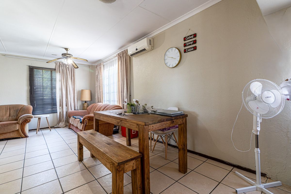 A living area featuring tiled flooring, a ceiling fan, and a wall-mounted air conditioning unit.