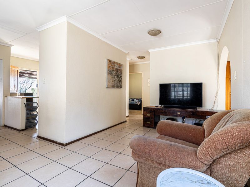 A living room featuring ceramic tile flooring, coved ceilings, and an open-plan layout leading to adjacent areas.