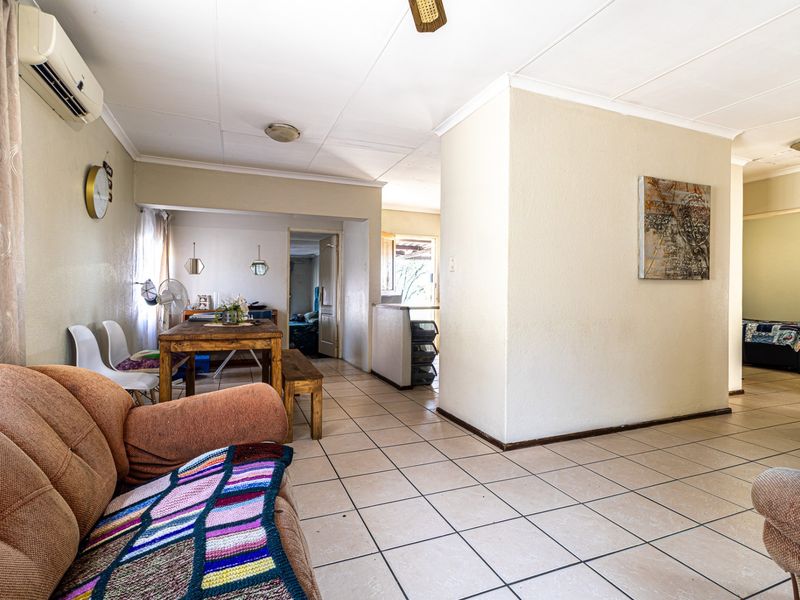 Open-plan living and dining area featuring ceramic floor tiles, a split-system air conditioner, and a ceiling fan, offering a functional layout.