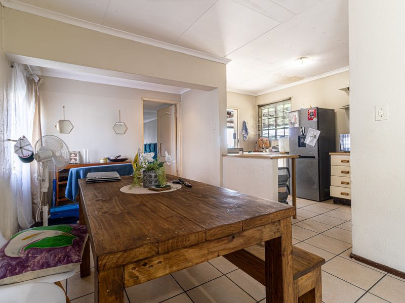 Open plan kitchen and dining area featuring tiled flooring and functional cabinetry, with visible ceiling maintenance required.