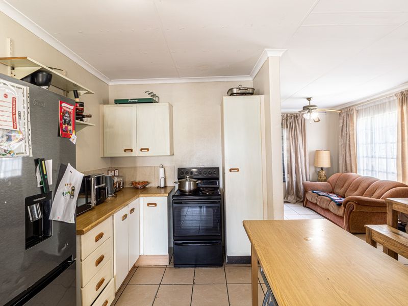 Open-plan kitchen and living area featuring tiled flooring, built-in cabinetry, and a freestanding stove, offering a functional layout for daily living.