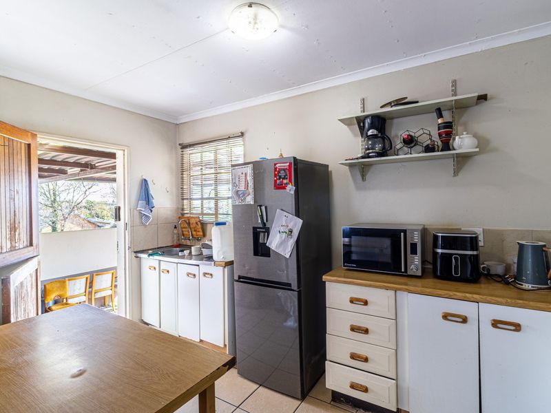 A functional kitchen featuring built-in cabinetry, laminate countertops, and direct access to an outdoor patio area.