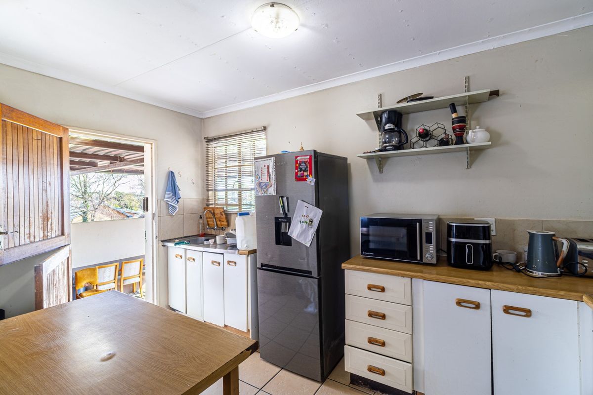 A functional kitchen featuring built-in cabinetry, laminate countertops, and direct access to an outdoor patio area.