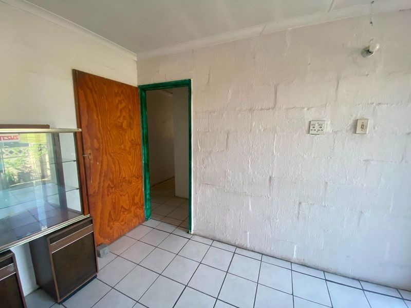 A sparsely furnished room featuring tiled flooring and an exposed blockwork wall, providing a blank canvas for potential renovation and interior design updates.