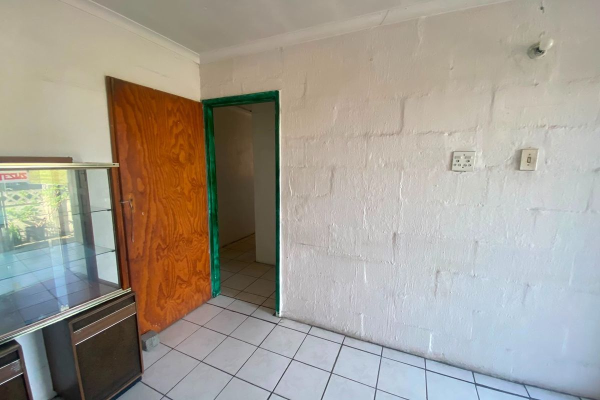 A sparsely furnished room featuring tiled flooring and an exposed blockwork wall, providing a blank canvas for potential renovation and interior design updates.
