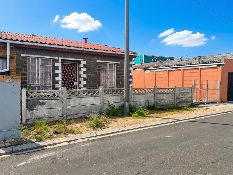Front exterior view of a single-story house featuring a tiled roof, security gate, and a precast concrete boundary wall.