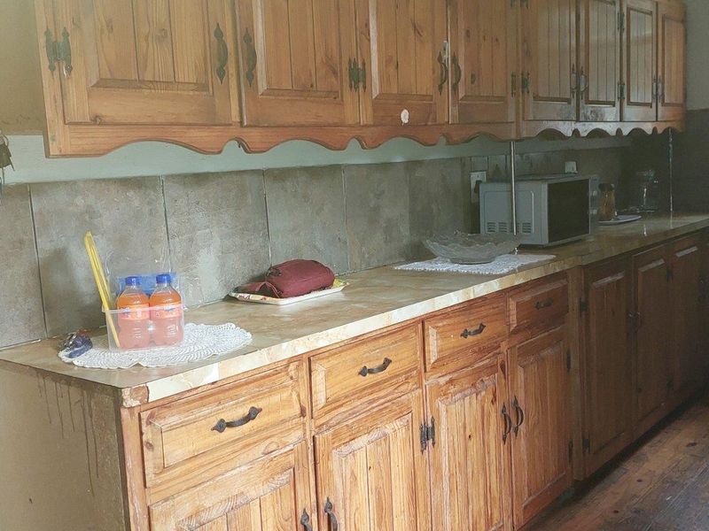 A dated kitchen featuring traditional timber cabinetry, tiled splashbacks, and laminate countertops, offering significant potential for a modern renovation.