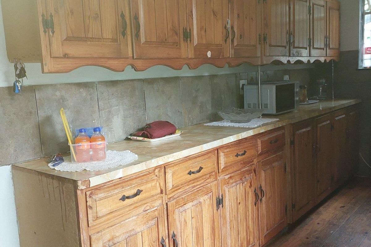 A dated kitchen featuring traditional timber cabinetry, tiled splashbacks, and laminate countertops, offering significant potential for a modern renovation.