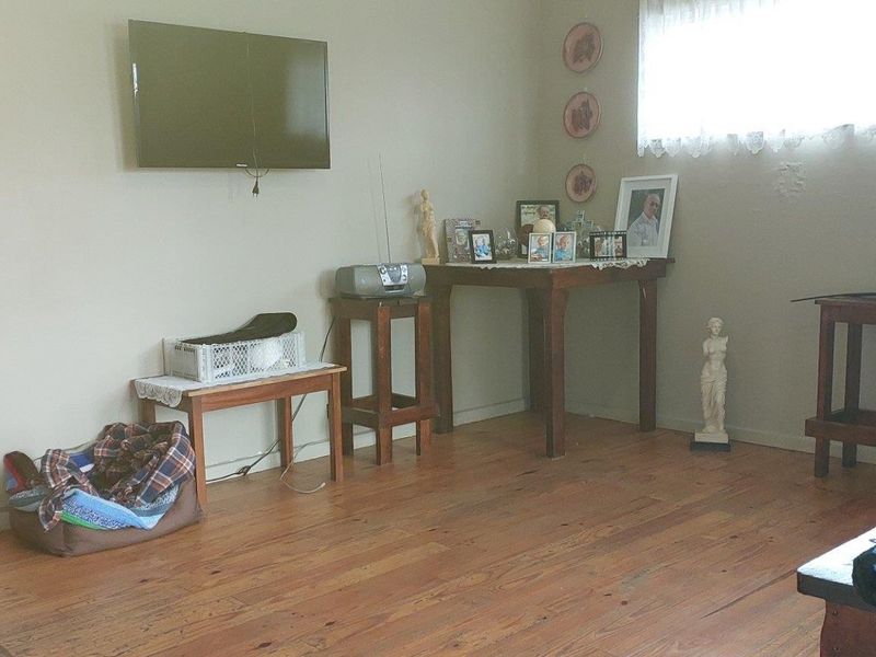 A living room featuring hardwood flooring and a wall-mounted television, offering a functional space with potential for modern updates.