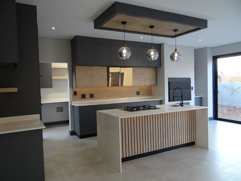 Modern kitchen featuring a central island with gas hob, sleek dark cabinetry, stone countertops, and a stylish slatted wood feature on the island base.