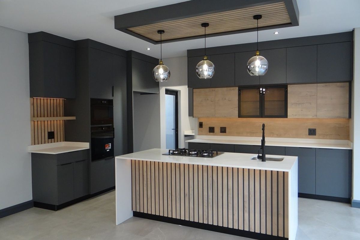 Modern, high-end kitchen featuring dark cabinetry, stone countertops, a central island with gas cooktop, and elegant slatted wood accents.