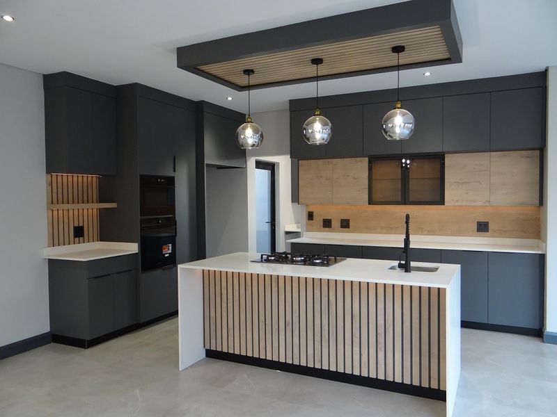 Modern, high-end kitchen featuring dark cabinetry, stone countertops, a central island with gas cooktop, and elegant slatted wood accents.