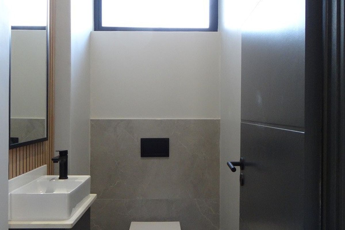 Modern guest powder room featuring a wall-mounted toilet, sleek vanity with vessel sink, and contemporary timber slat wall detailing.