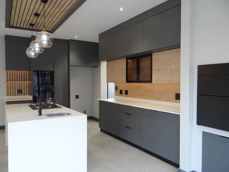 Modern kitchen featuring dark grey cabinetry, light wood accents, a central island with a gas hob, and a stylish timber slat ceiling detail.