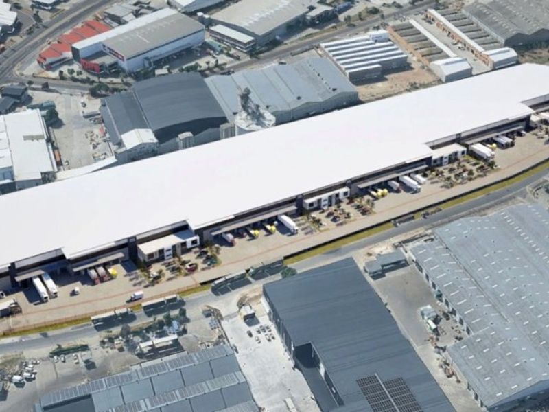 Aerial view of a large-scale industrial warehouse facility featuring extensive loading docks and a paved yard area within an industrial park.