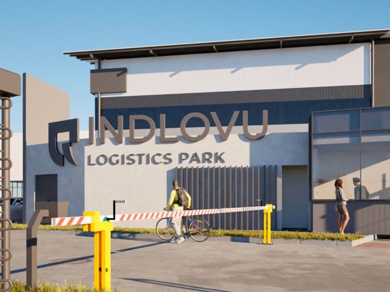 Modern industrial logistics park entrance featuring a secure boom gate, guard booth, and prominent building signage.