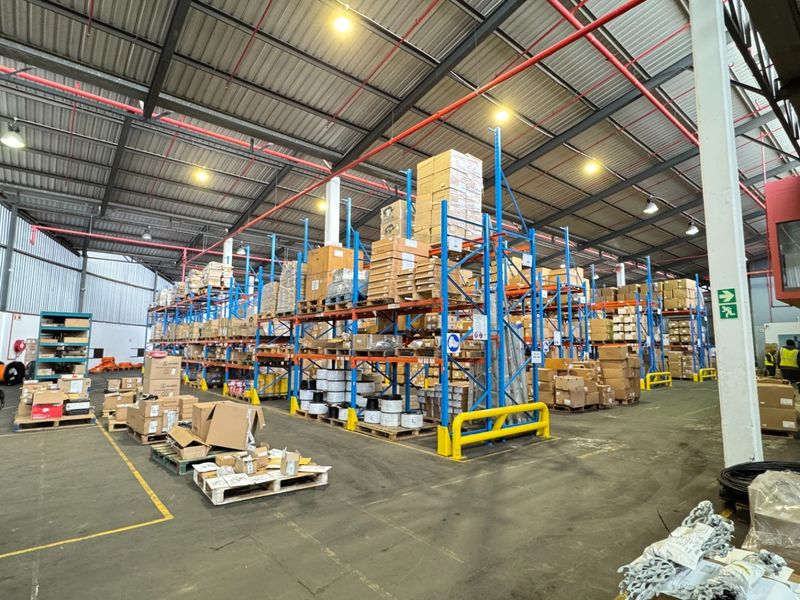 Spacious industrial warehouse featuring high-bay ceilings, extensive steel racking systems, fire sprinkler infrastructure, and durable concrete flooring suitable for logistics or storage operations.