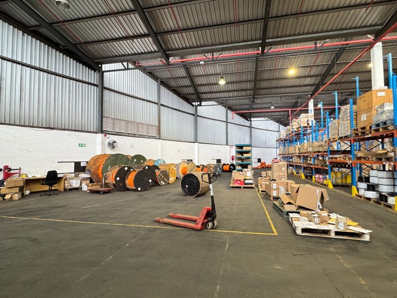 Spacious industrial warehouse featuring high ceilings, exposed steel roof structure, heavy-duty storage racking, and durable concrete flooring suitable for logistics or manufacturing operations.
