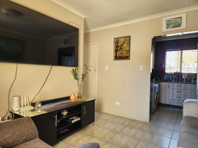 Open plan living area featuring tiled flooring with an adjacent kitchen space, providing a functional layout for daily living.