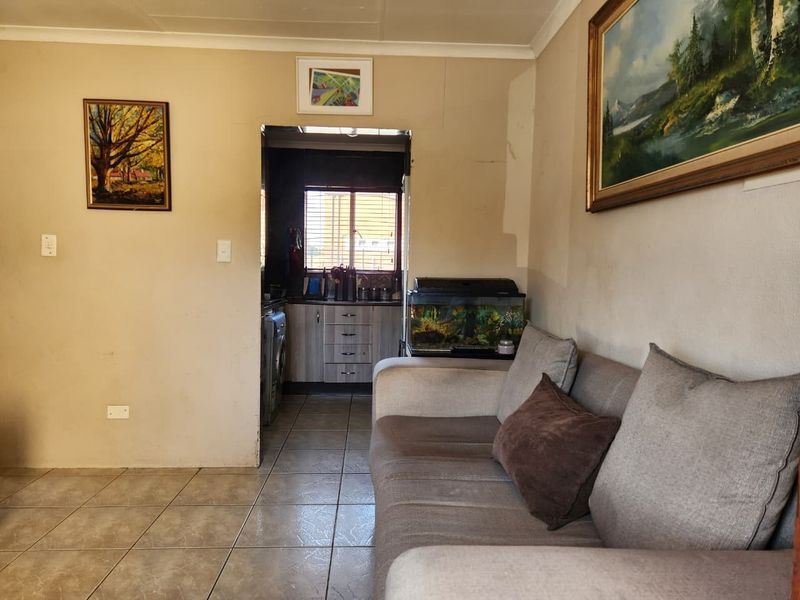 Open plan living area featuring tiled flooring and a view into the adjacent kitchen space with built-in cabinetry.
