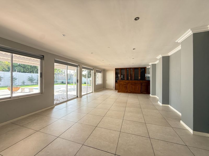 Spacious living area featuring large sliding glass doors, tiled flooring, recessed lighting, and a built-in wooden bar unit.