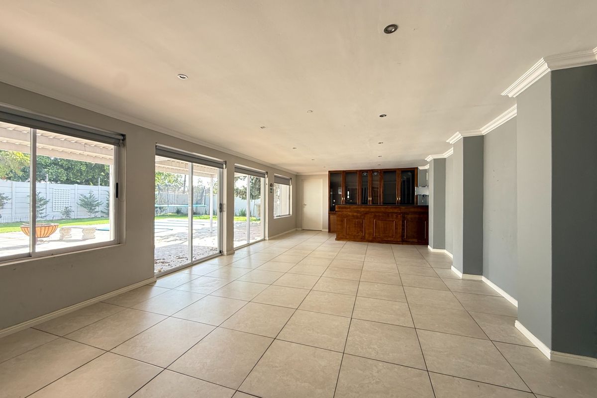 Spacious living area featuring large sliding glass doors, tiled flooring, recessed lighting, and a built-in wooden bar unit.
