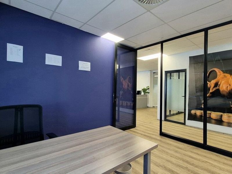 Modern commercial office space featuring glass partition walls, suspended ceilings, and durable laminate flooring, providing a professional and bright work environment.